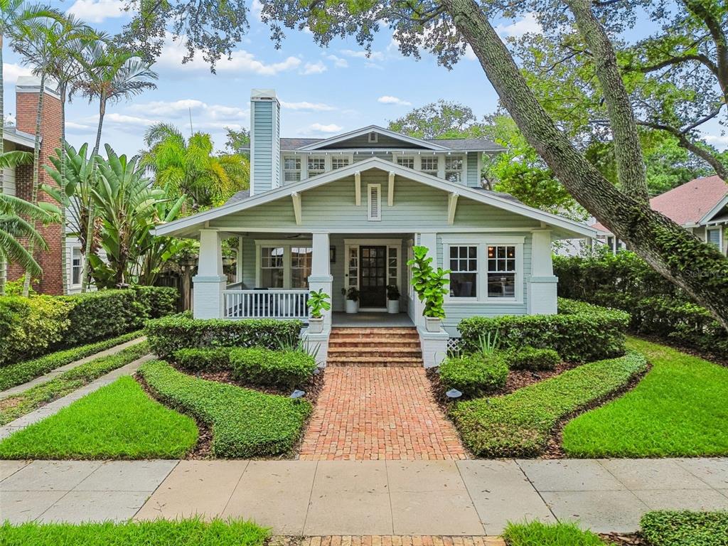 A light green craftsman-style house features a brick walkway, a front porch, and mature landscaping — 712 S ORLEANS AVENUE, TAMPA, FL