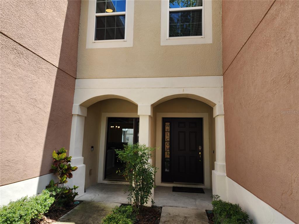 The exterior entrance of a two-story home features a covered porch with two arched openings — 26541 CHIMNEY SPIRE LANE, WESLEY CHAPEL, FL