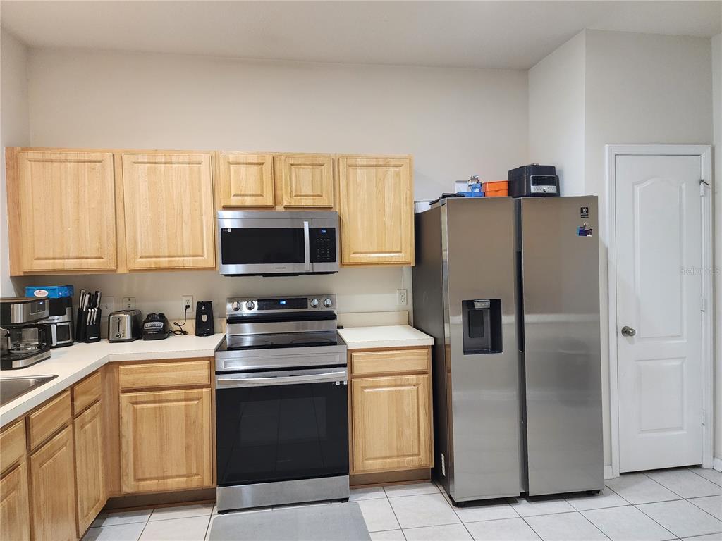 A kitchen features light wood cabinets, stainless steel appliances, and tile flooring — 26541 CHIMNEY SPIRE LANE, WESLEY CHAPEL, FL