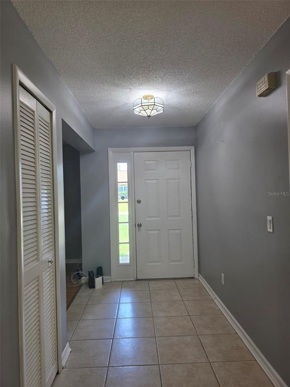 An entryway features light gray walls, a tiled floor, a white door, and a ceiling light — 2473 BECK CIRCLE, DELTONA, FL