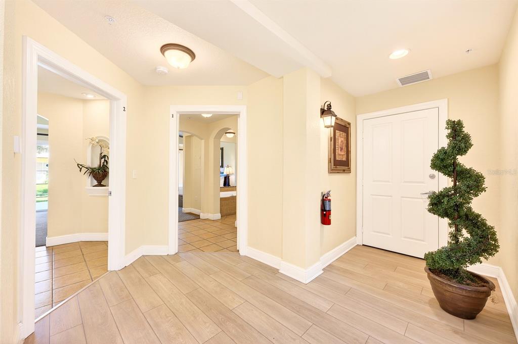 A bright entryway with light wood-look tile flooring, a white door, and two arched doorways — 1302 SEVEN EAGLES COURT UNIT 1302, REUNION, FL