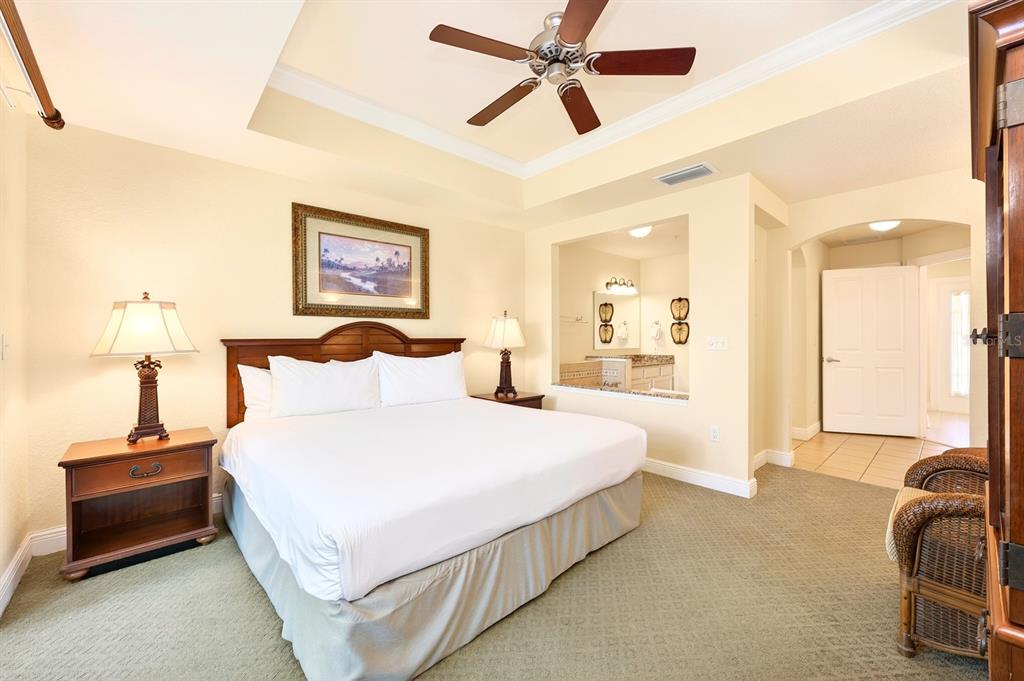 A bedroom with a king bed, ceiling fan, and an open view into the bathroom — 1302 SEVEN EAGLES COURT UNIT 1302, REUNION, FL