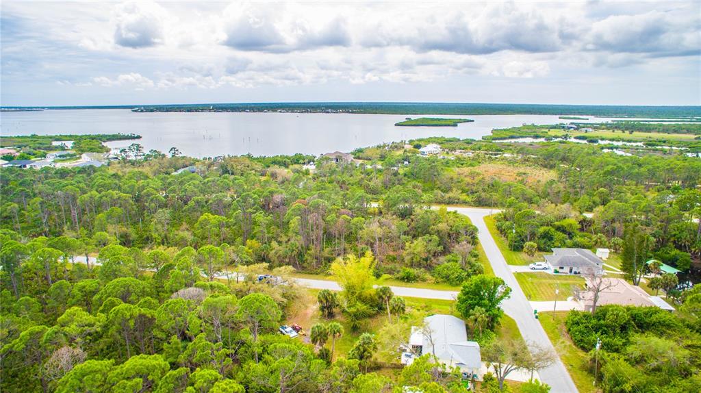 An aerial view shows a wooded residential area near a large body of water — 12253 ENDICOTT LANE, PORT CHARLOTTE, FL