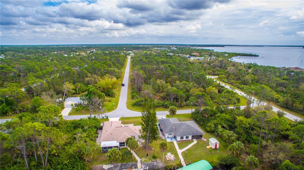 An aerial view shows two houses near a body of water surrounded by dense trees — 12253 ENDICOTT LANE, PORT CHARLOTTE, FL