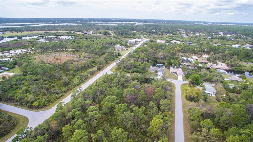 An aerial view shows a residential neighborhood with paved roads surrounded by dense green trees — 12253 ENDICOTT LANE, PORT CHARLOTTE, FL