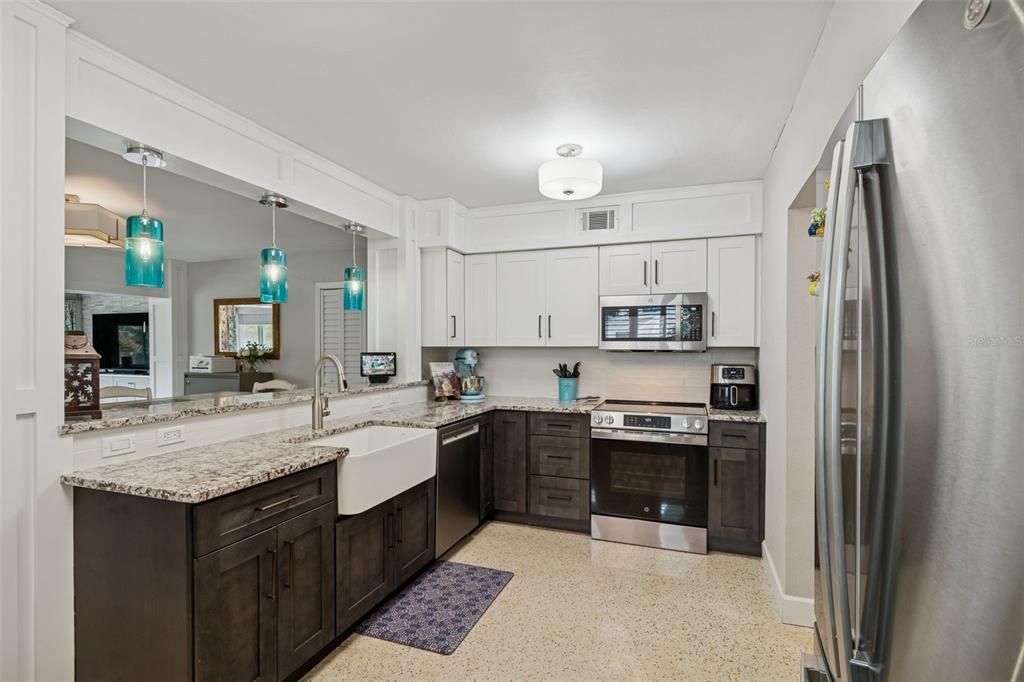 A dining area with a wooden table and chairs sits adjacent to a kitchen counter — 2427 BAYWOOD DRIVE W, DUNEDIN, FL