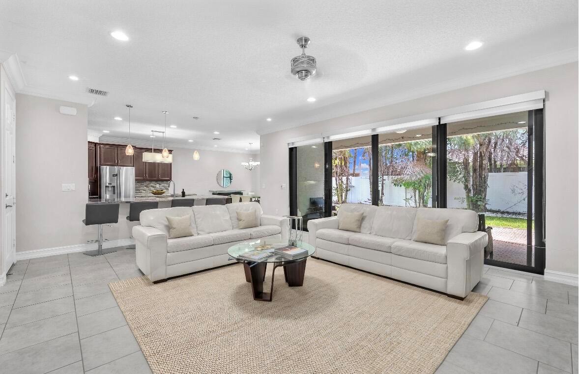 A living room with two white sofas, a glass coffee table, and sliding glass doors — 8104 Rainforest Jasper Lane, Delray Beach FL 33446, DELRAY BEACH, FL
