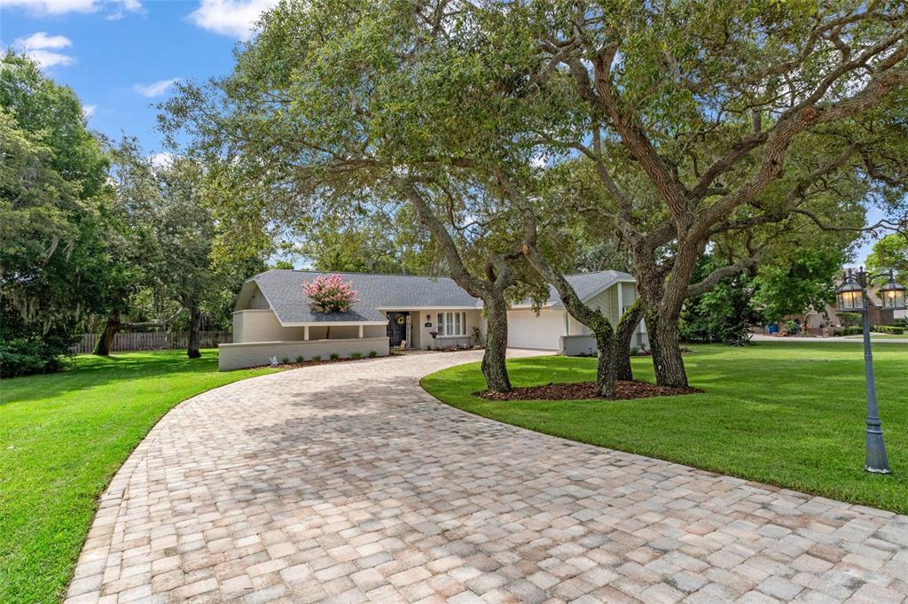A single-story house with a paved driveway and large oak trees in the front yard — 5008 CUMBERLAND LANE, SPRING HILL, FL