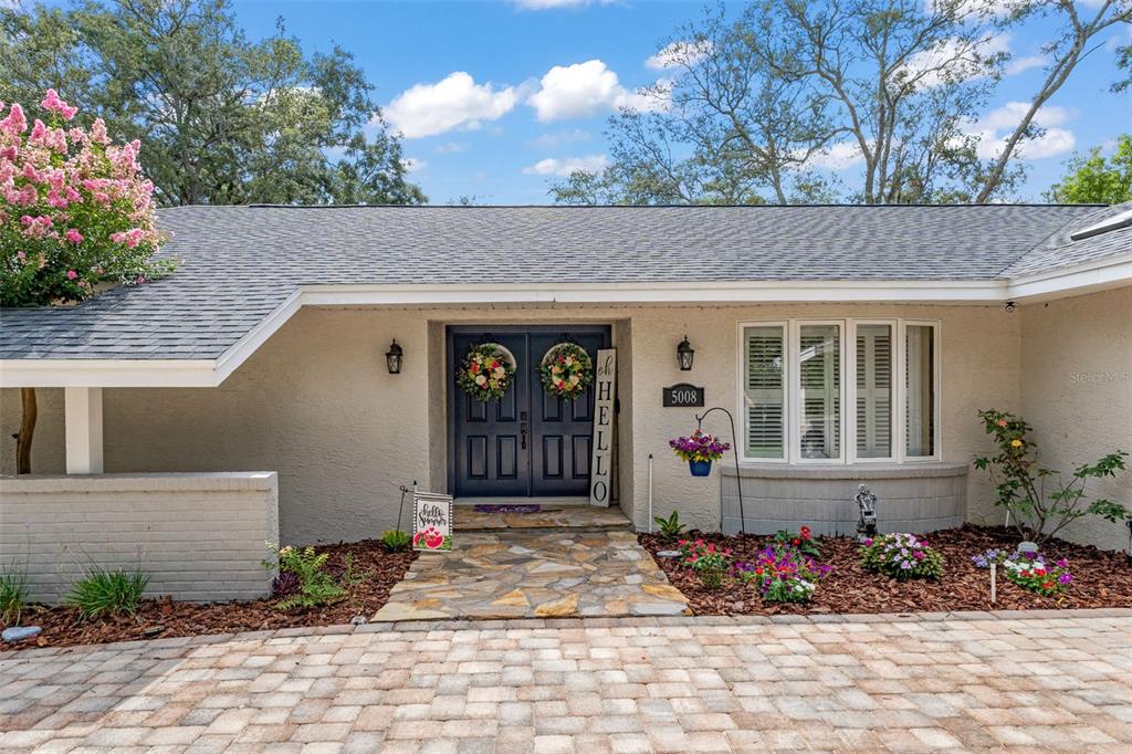 The exterior of a single-story home features a stone walkway leading to double front doors — 5008 CUMBERLAND LANE, SPRING HILL, FL