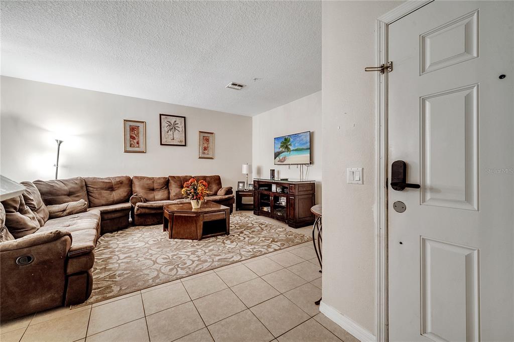 A concrete walkway leads between two yellow stucco walls to two adjacent residential entry doors — 2820 OAKWATER DRIVE UNIT 2820, KISSIMMEE, FL