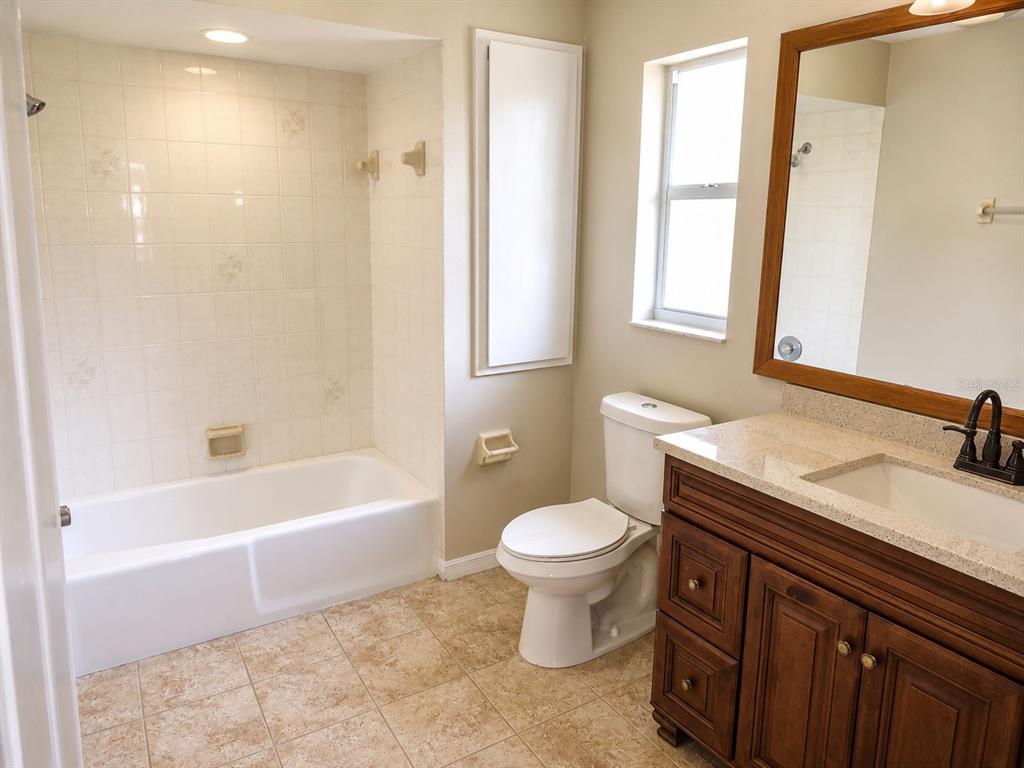 A bathroom featuring a tiled tub-shower combo, a white toilet, and a wooden vanity cabinet — 1002 TORGERSON STREET, NORTH PORT, FL