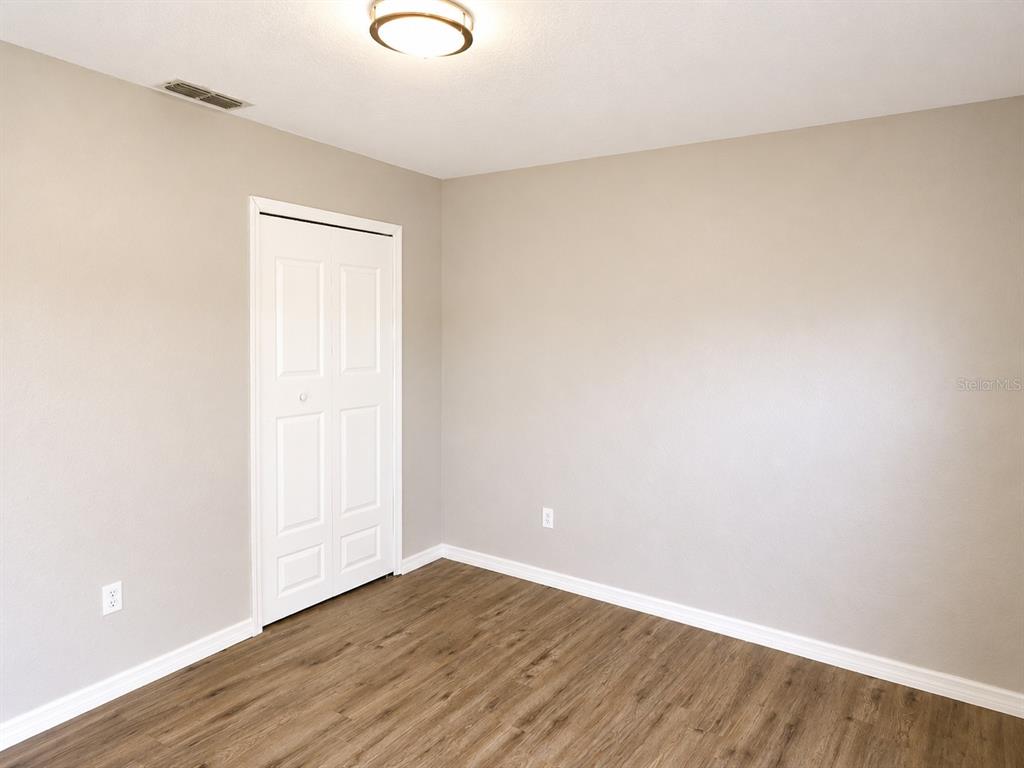 An empty room features light-colored walls, wood-look flooring, a white closet door, and a ceiling light — 1002 TORGERSON STREET, NORTH PORT, FL