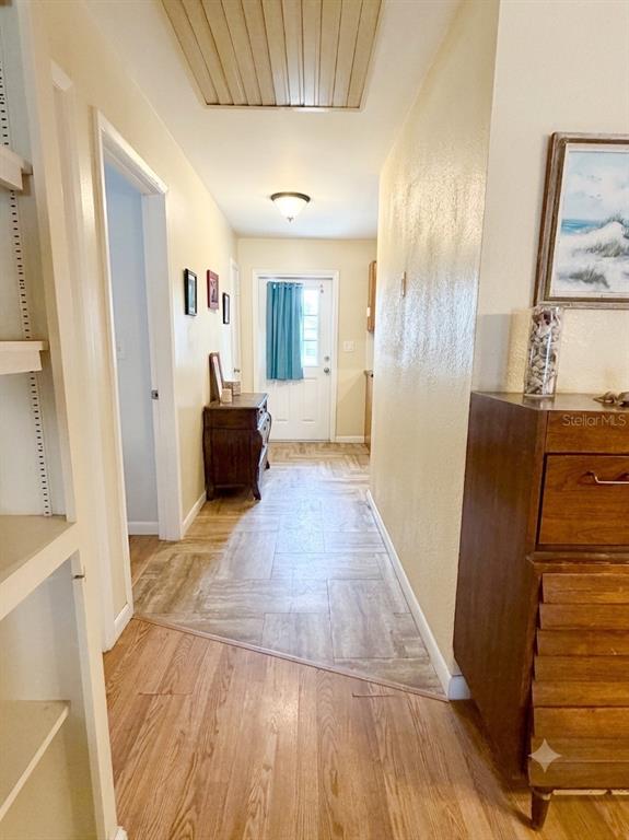 A hallway features wood-look flooring, a wooden dresser, and a door leading to the exterior — 700 W DAMPIER STREET, INVERNESS, FL