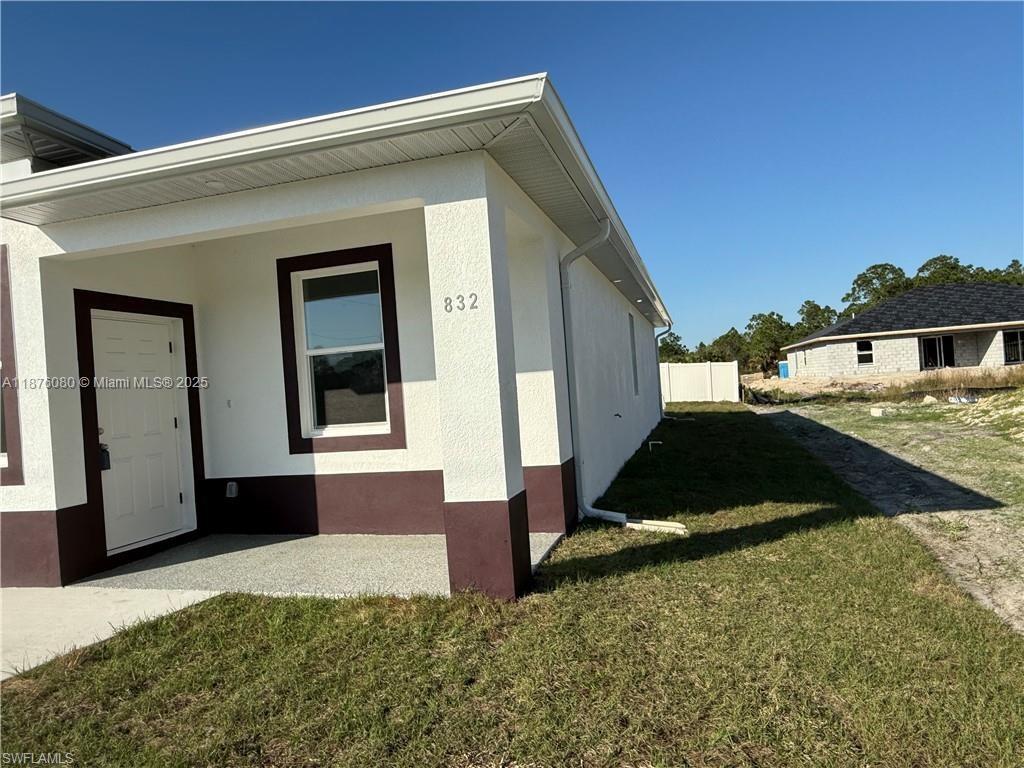 The exterior of a white house features a covered entryway, brown trim, and a numbered address — 832 HOLMES AVE # 832, Lehigh Acres FL 33974, LEHIGH ACRES, FL