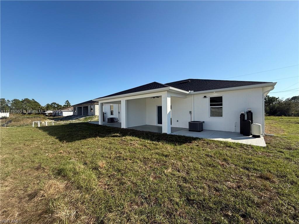 The exterior of a white house features a covered patio and a grassy backyard — 832 HOLMES AVE # 832, Lehigh Acres FL 33974, LEHIGH ACRES, FL
