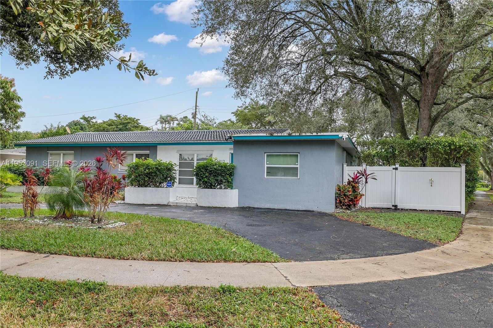 A single-story house with a gray and white exterior features a paved driveway and landscaping — 5712 Monroe St, Hollywood FL 33023, HOLLYWOOD, FL