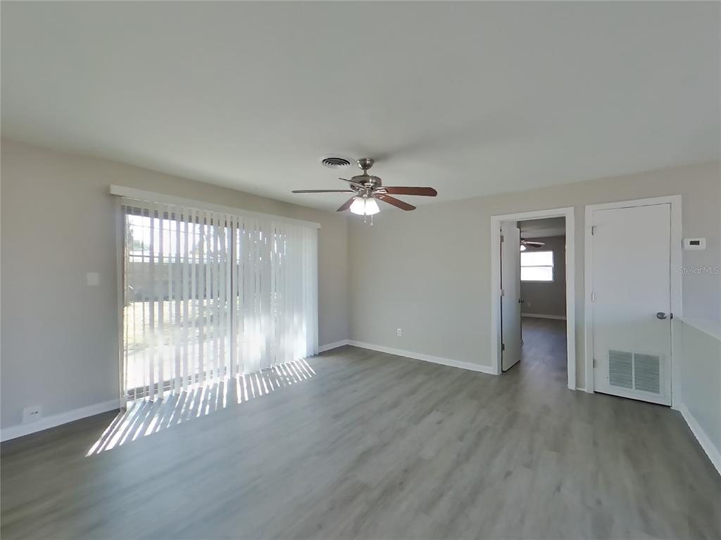 A living room with light gray flooring, a ceiling fan, and sliding glass patio doors — 1122 IBSEN AVENUE, ORLANDO, FL