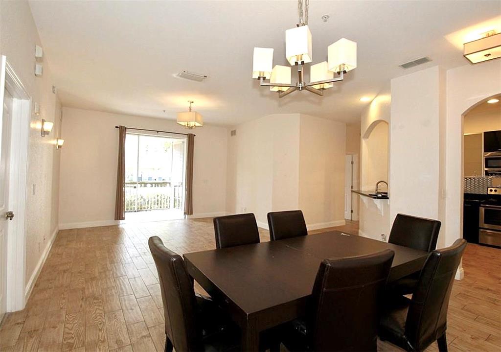 A dining room with a dark table and chairs, tile flooring, and a chandelier — 3001 LAUREL PARK LANE UNIT 105, KISSIMMEE, FL