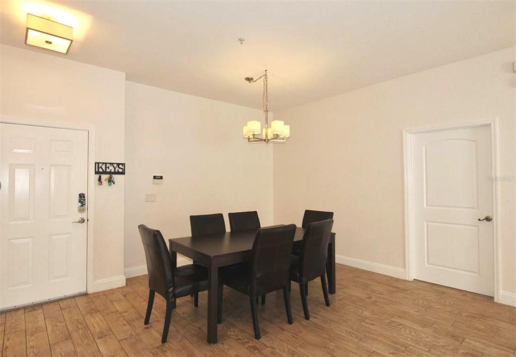 A dining room features a dark wood table, six chairs, and a hanging light fixture — 3001 LAUREL PARK LANE UNIT 105, KISSIMMEE, FL