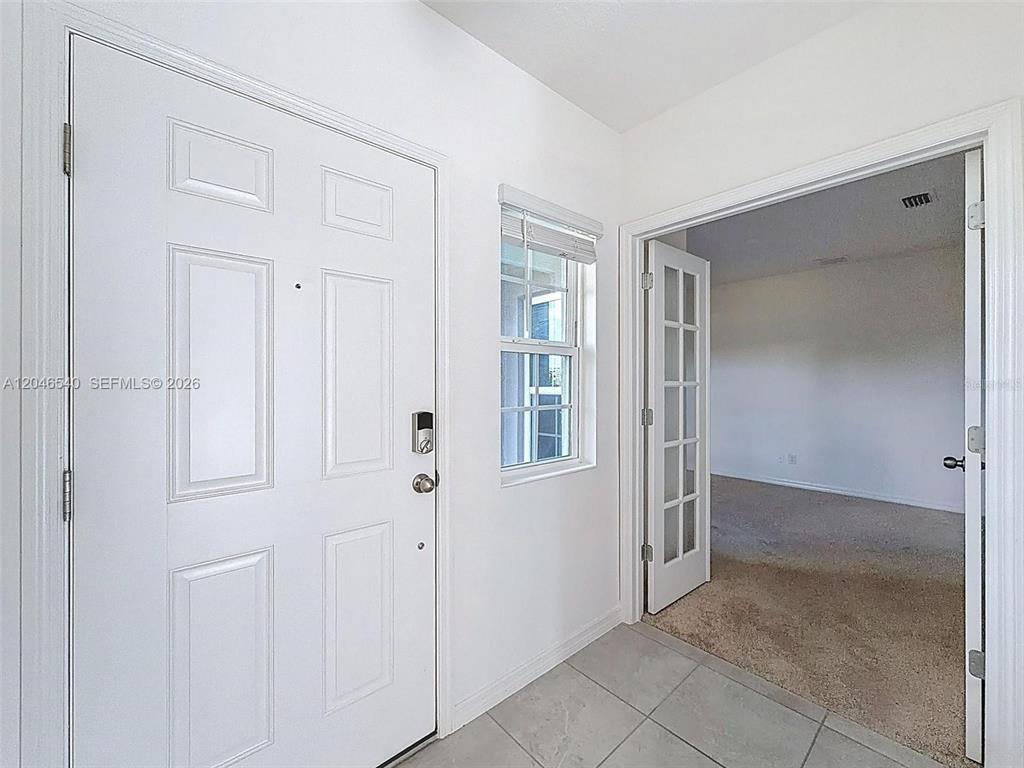 An entryway features a white front door, a window with blinds, and a carpeted room — 857 SCRUB OAK HAMMOCK ROAD, DAVENPORT, FL