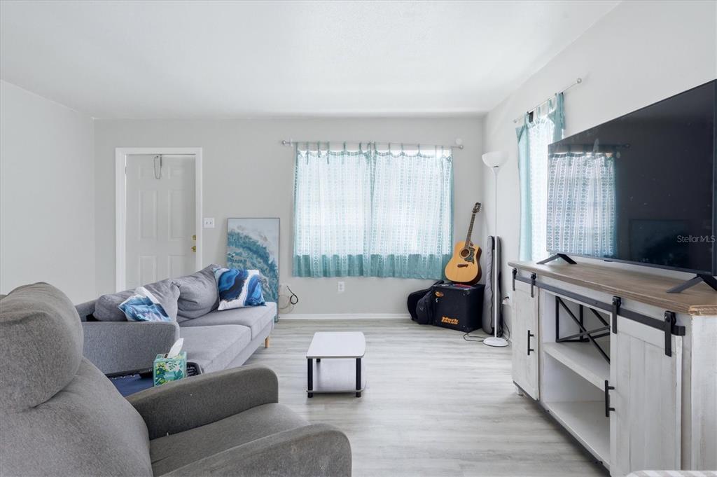A living room features light gray flooring, a gray sofa, and a white media console — 1805 MARBETH STREET UNIT 1805/1807, SARASOTA, FL