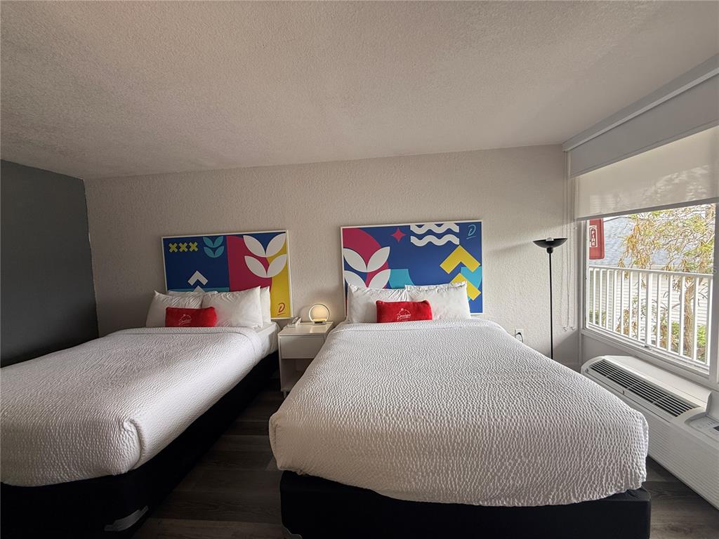 A hotel room features two beds with colorful headboards, a nightstand, and a window view — 2930 POLYNESIAN ISLES BOULEVARD UNIT 233, KISSIMMEE, FL