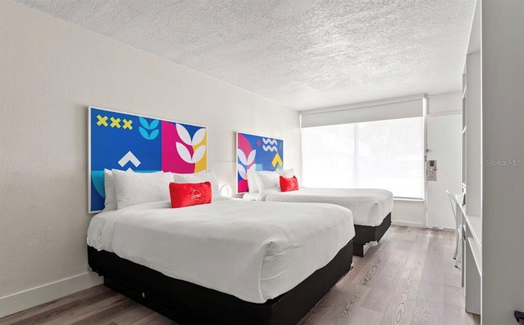 A hotel room features two beds with colorful headboards and light wood-look flooring — 2930 POLYNESIAN ISLES BOULEVARD UNIT 233, KISSIMMEE, FL