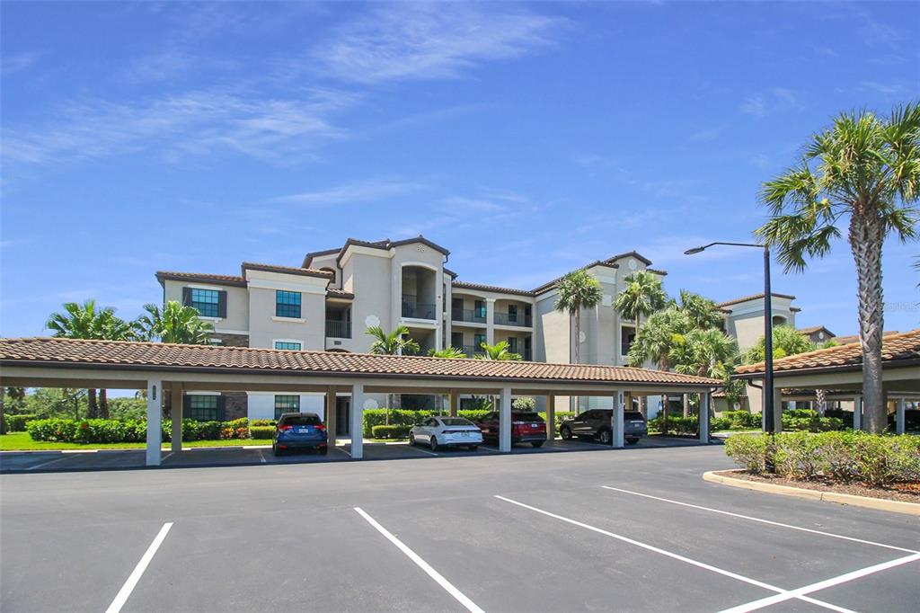 A multi-story apartment building with a covered parking area in the foreground — 16904 VARDON TERRACE UNIT 204, BRADENTON, FL