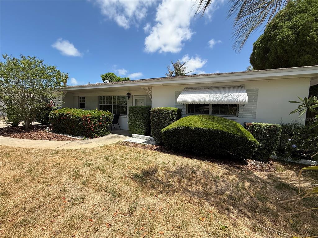 A single-story white house features a lawn, manicured hedges, and a metal window awning — 11537 63RD AVENUE, SEMINOLE, FL