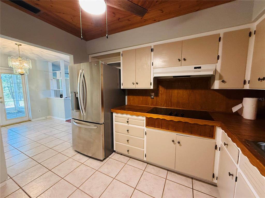 A kitchen features light-colored cabinets, a stainless steel refrigerator, wood countertops, and tile flooring — 11537 63RD AVENUE, SEMINOLE, FL