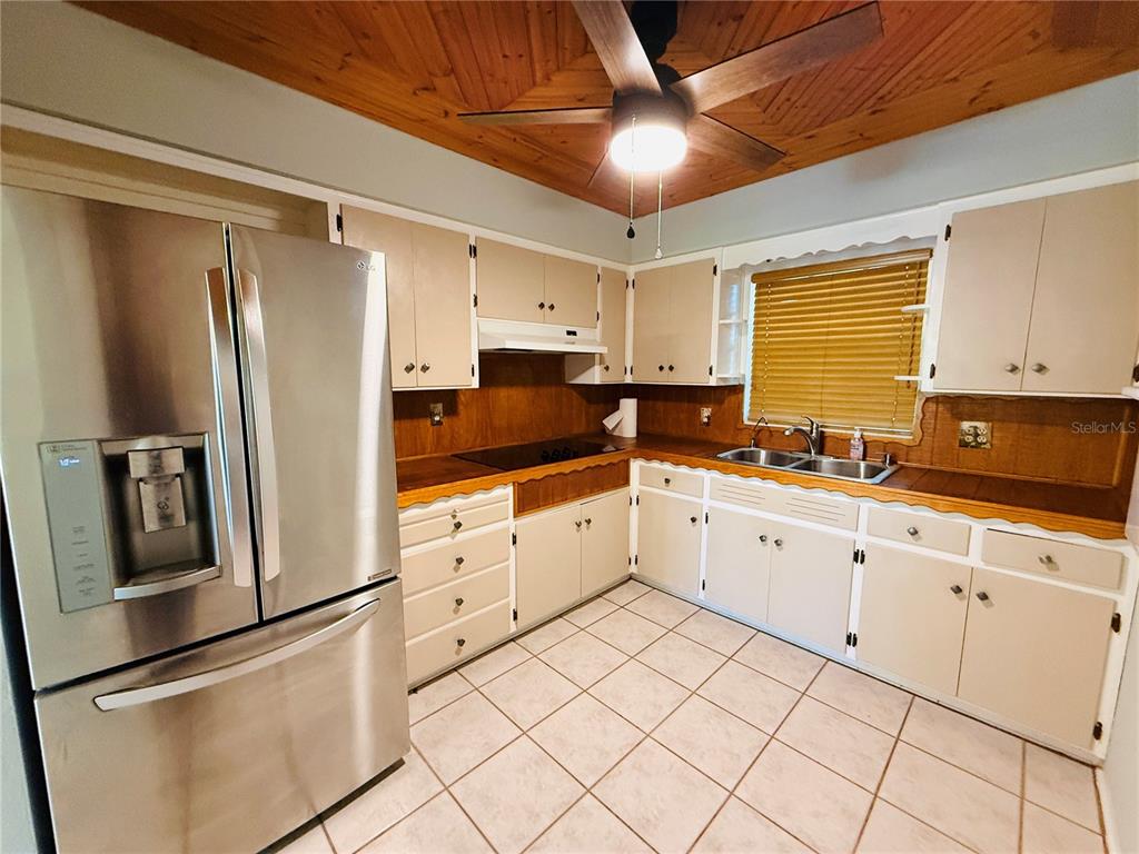 A kitchen features light-colored cabinets, wood countertops, a stainless steel refrigerator, and a wood-paneled ceiling — 11537 63RD AVENUE, SEMINOLE, FL