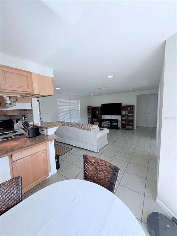 A kitchen with light wood cabinets overlooks a living room featuring tile flooring — 3219 CAMBRIDGE DRIVE, SARASOTA, FL
