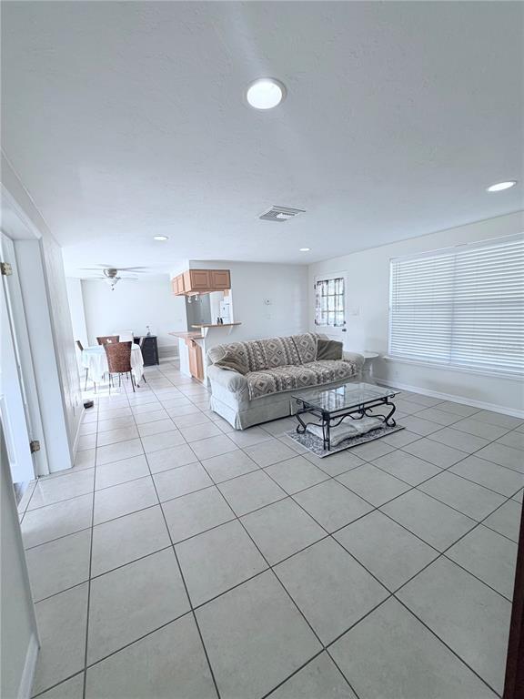 A living room with light tile flooring, a patterned sofa, and an adjacent dining area — 3219 CAMBRIDGE DRIVE, SARASOTA, FL