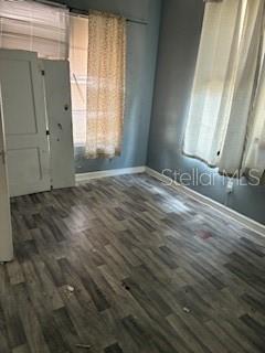 An empty bedroom features light gray wood-look flooring, blue walls, and white window curtains — 1401 E 24TH AVENUE, TAMPA, FL