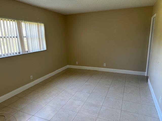 An empty room with beige walls, tile flooring, and vertical blinds on a window — 7605 NW 5th Place # 106, Margate FL 33063, MARGATE, FL