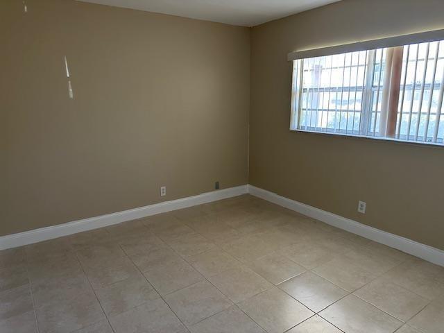 An empty room with tan walls, tile flooring, and a window with vertical blinds — 7605 NW 5th Place # 106, Margate FL 33063, MARGATE, FL