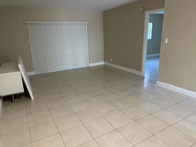 An empty room with beige tile flooring, a sliding glass door, and a doorway entrance — 7605 NW 5th Place # 106, Margate FL 33063, MARGATE, FL