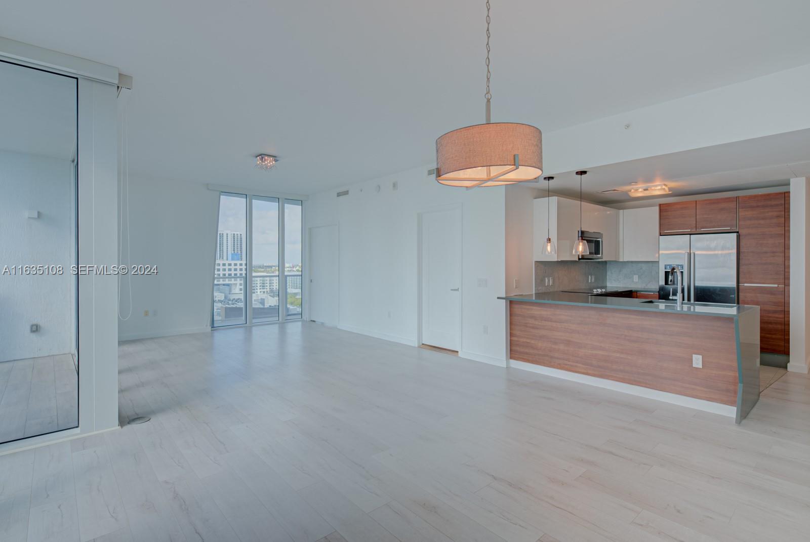An open-concept living area features light wood flooring, a modern kitchen, and floor-to-ceiling windows — 601 NE 27th St # 1502, Miami FL 33137, MIAMI, FL