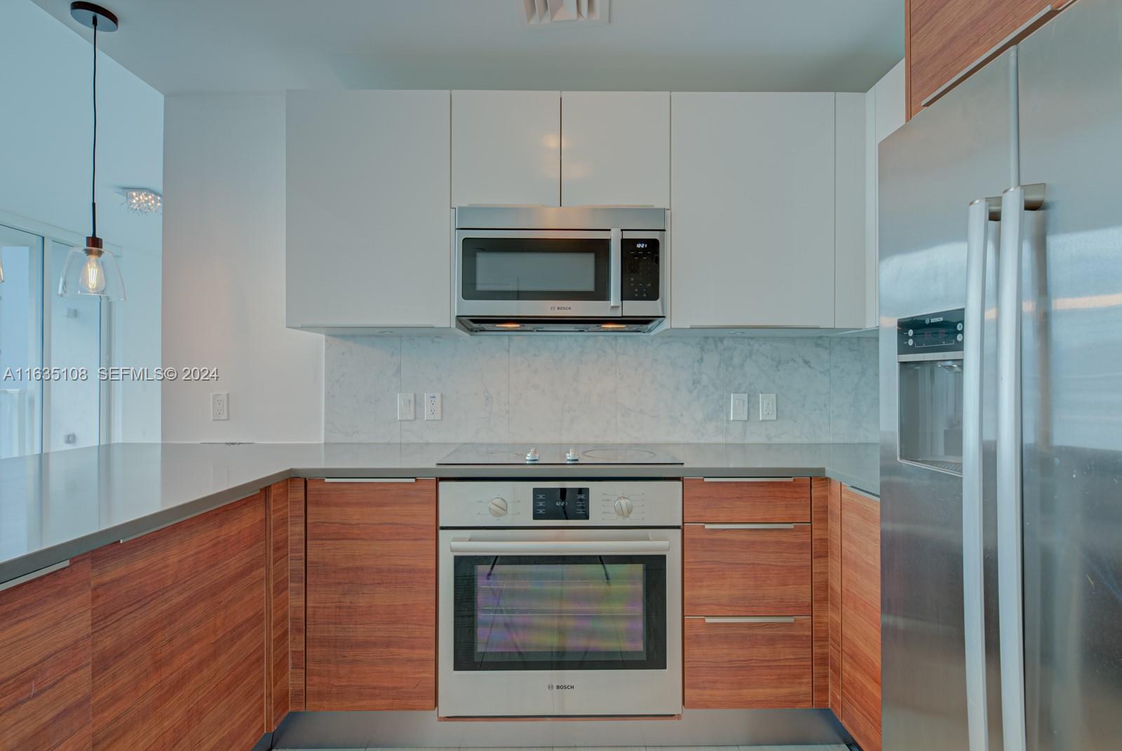A modern kitchen features wood-grain lower cabinets, white upper cabinets, and stainless steel appliances — 601 NE 27th St # 1502, Miami FL 33137, MIAMI, FL