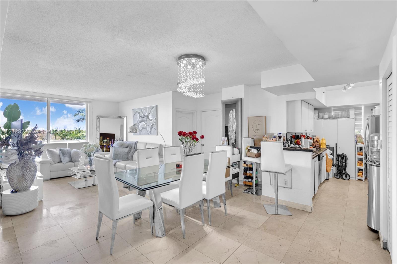 A bright, open-concept living and dining area features white furniture, a glass table, and tile flooring — 5077 NW 7th St # 517, Miami FL 33126, MIAMI, FL