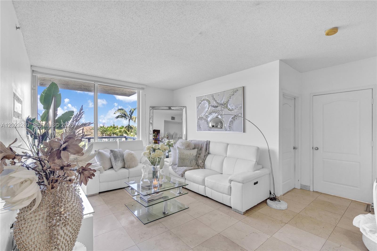 A bright living room features white leather sofas, a glass coffee table, and tile flooring — 5077 NW 7th St # 517, Miami FL 33126, MIAMI, FL