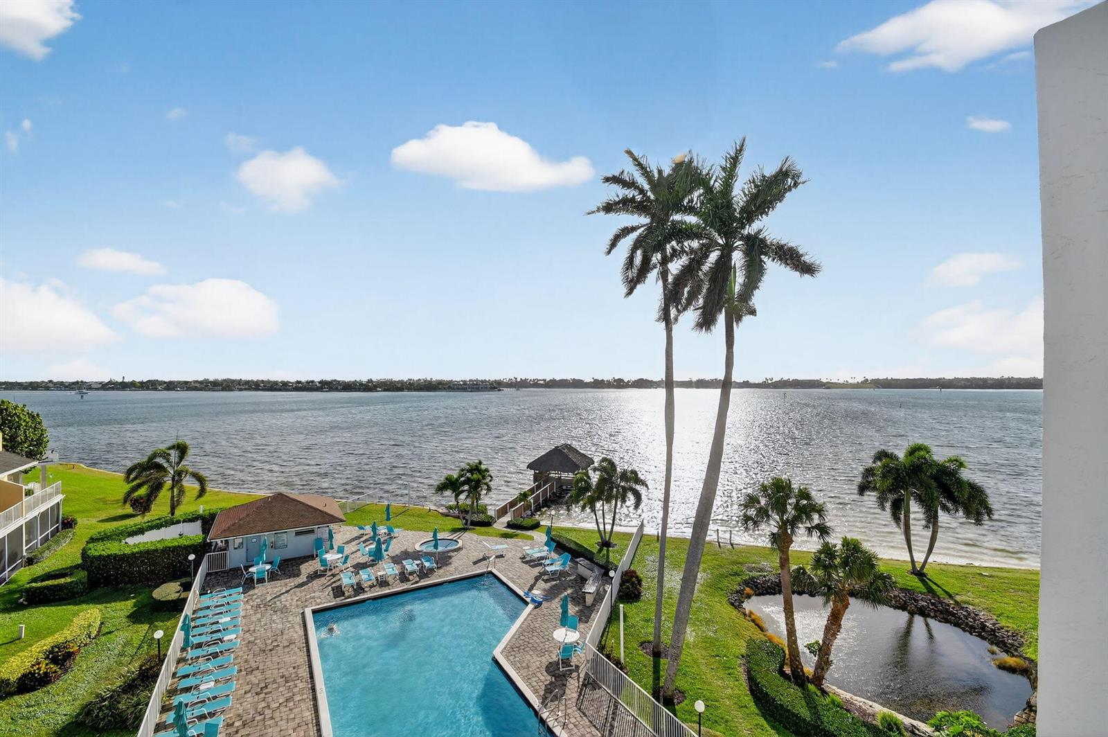 An elevated view shows a swimming pool, palm trees, and a small pond by the water — 8200 Lakeshore Drive # 507, Hypoluxo FL 33462, HYPOLUXO, FL