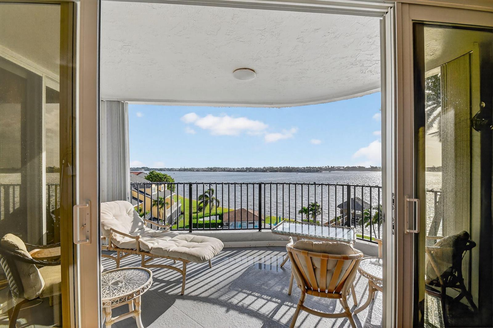 A balcony with lounge chairs and a table overlooks a body of water — 8200 Lakeshore Drive # 507, Hypoluxo FL 33462, HYPOLUXO, FL