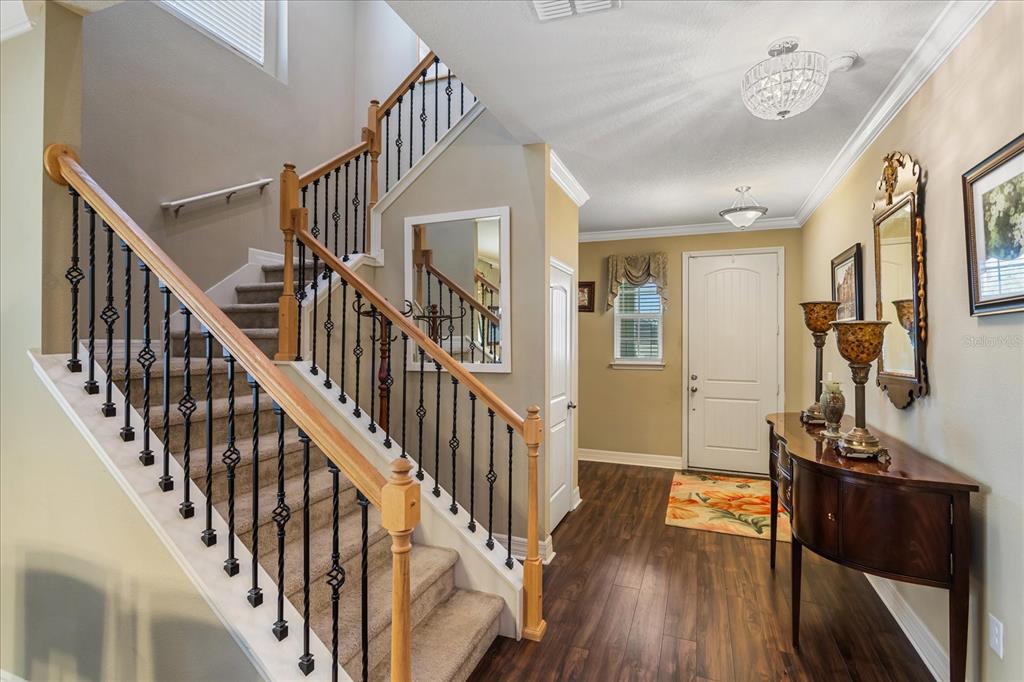 An entryway features a carpeted staircase with iron railings, wood flooring, and a console table — 4914 GRASSENDALE TERRACE, SANFORD, FL