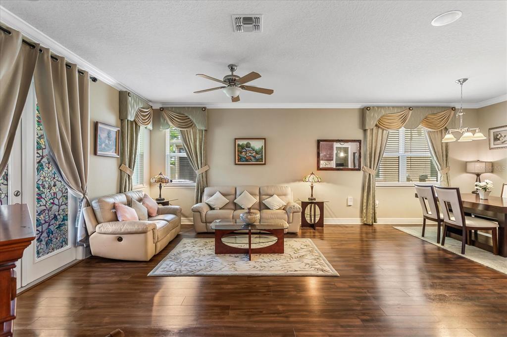 A living room with hardwood floors, a beige sofa, a coffee table, and dining area — 4914 GRASSENDALE TERRACE, SANFORD, FL