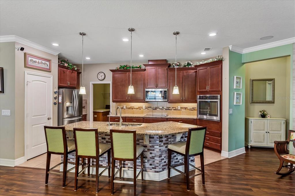 A kitchen features dark wood cabinets, granite countertops, a tiled island, and four green chairs — 4914 GRASSENDALE TERRACE, SANFORD, FL