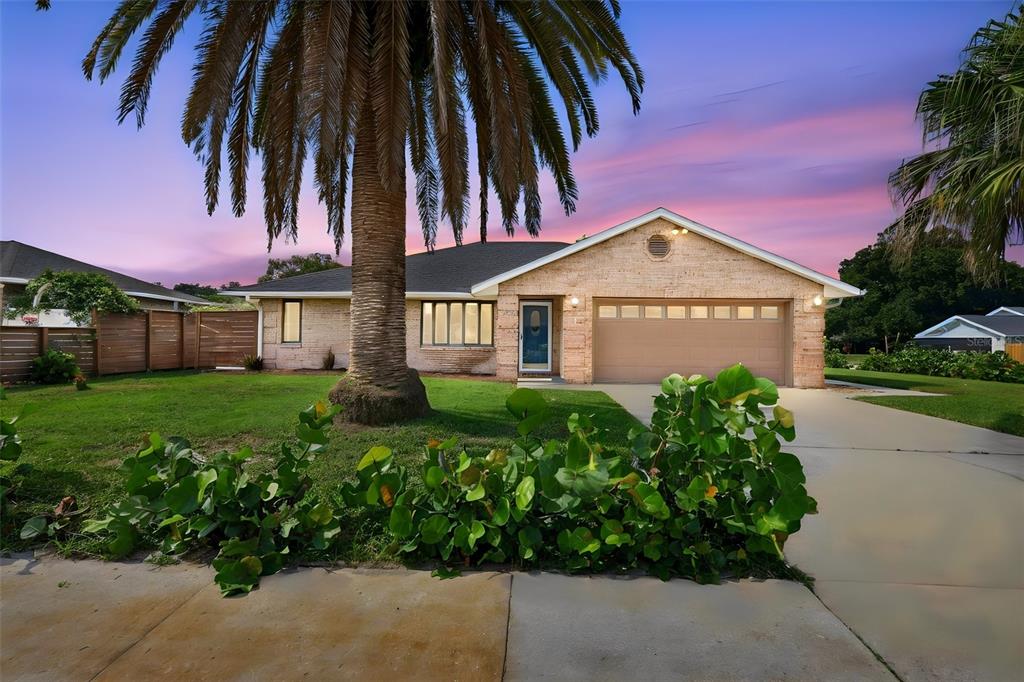 A single-story brick house with a two-car garage and a large palm tree in front — 5825 ALSTRUM DRIVE, PORT ORANGE, FL