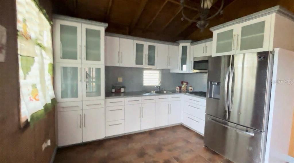 A kitchen features white cabinets, stainless steel appliances, and dark tile flooring — CARRETERA 779 KM 9.9 INT. BO. CEDRO ARRIBA, NARANJITO, PR