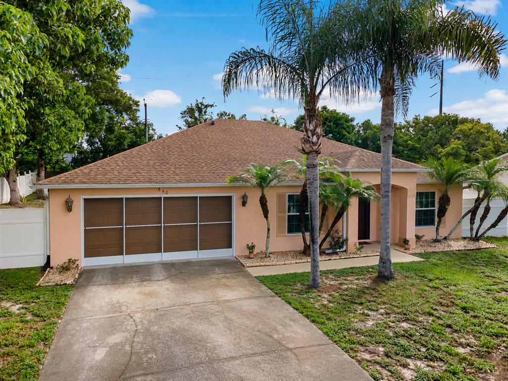 A single-story house with a tan exterior, a brown shingled roof, and a two-car garage — 640 FAIRHAVEN STREET, DELTONA, FL
