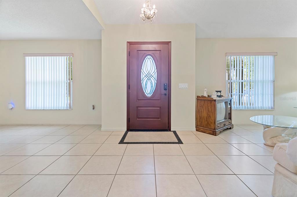 A bright entryway features light tile flooring, a central wooden front door, and two windows — 640 FAIRHAVEN STREET, DELTONA, FL